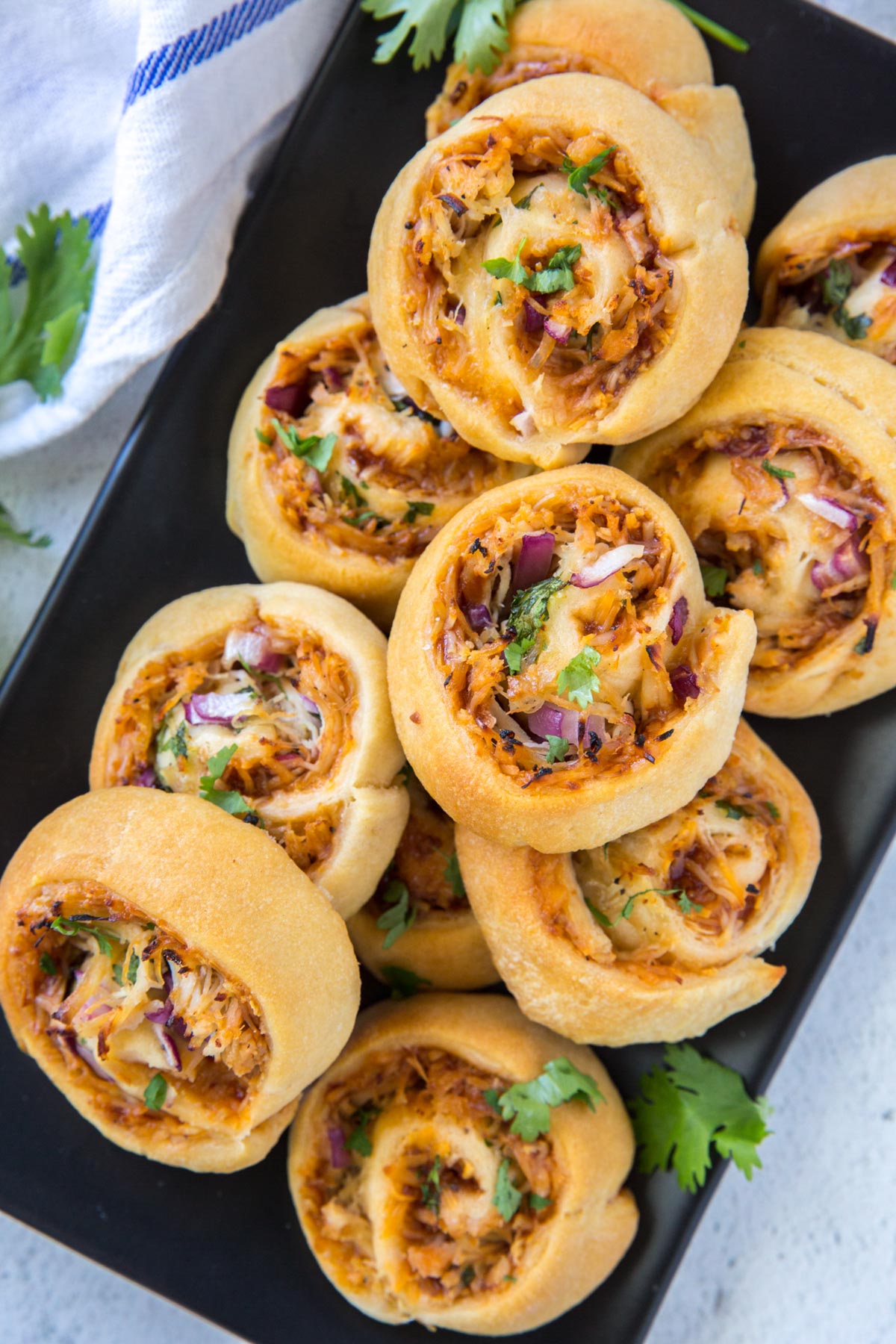 bbq chicken pizza rolls stacked and on a black platter