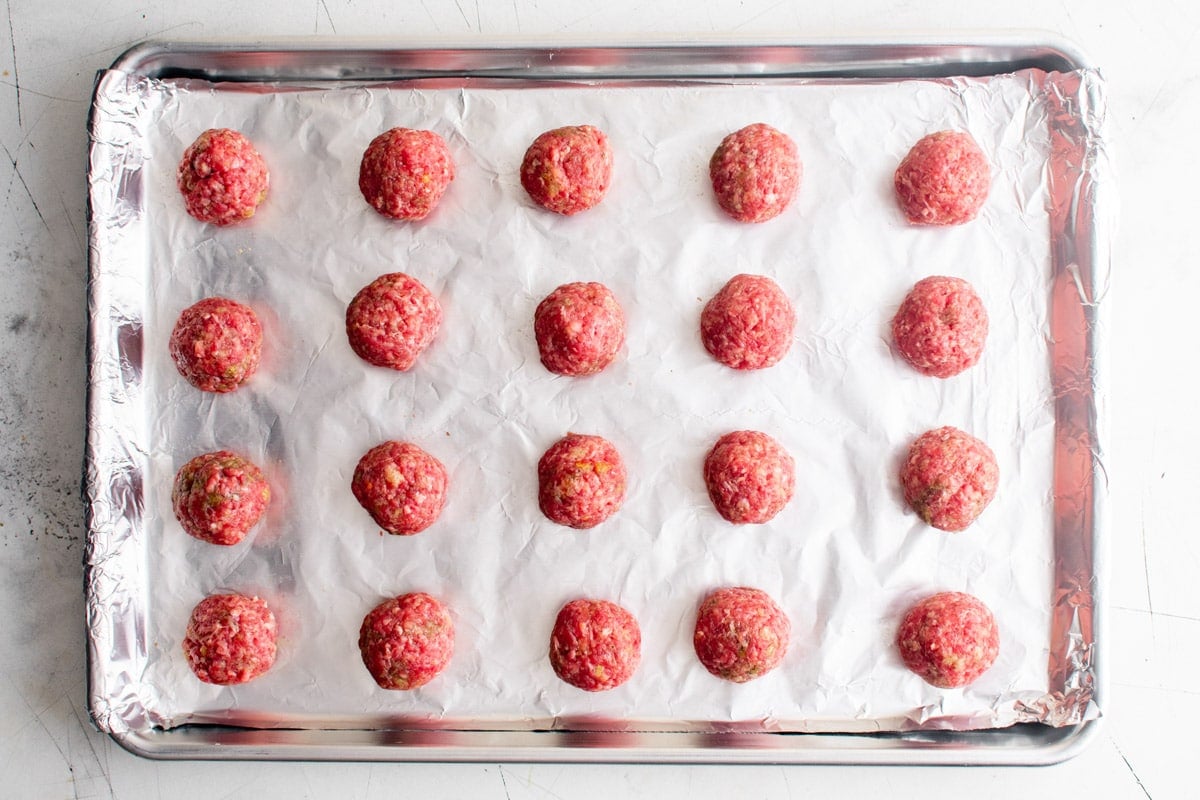 raw meatballs on a foil lined baking sheet