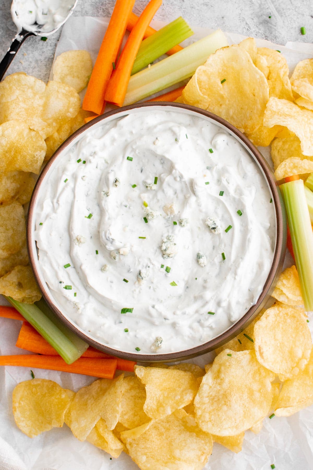 blue cheese dip in a bowl surrounded by carrot and celery sticks and potato chips