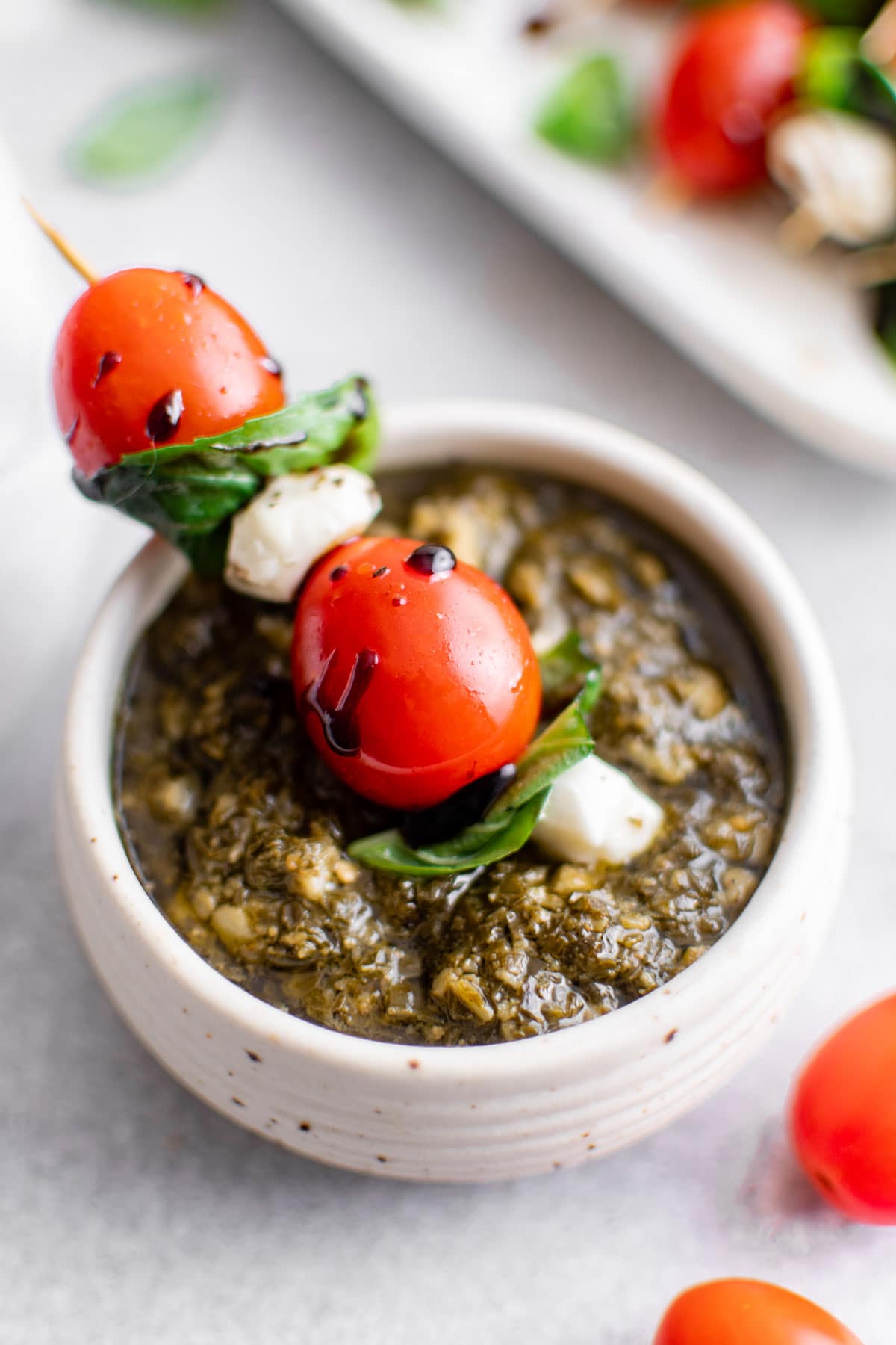caprese salad on a stick dipped in pesto