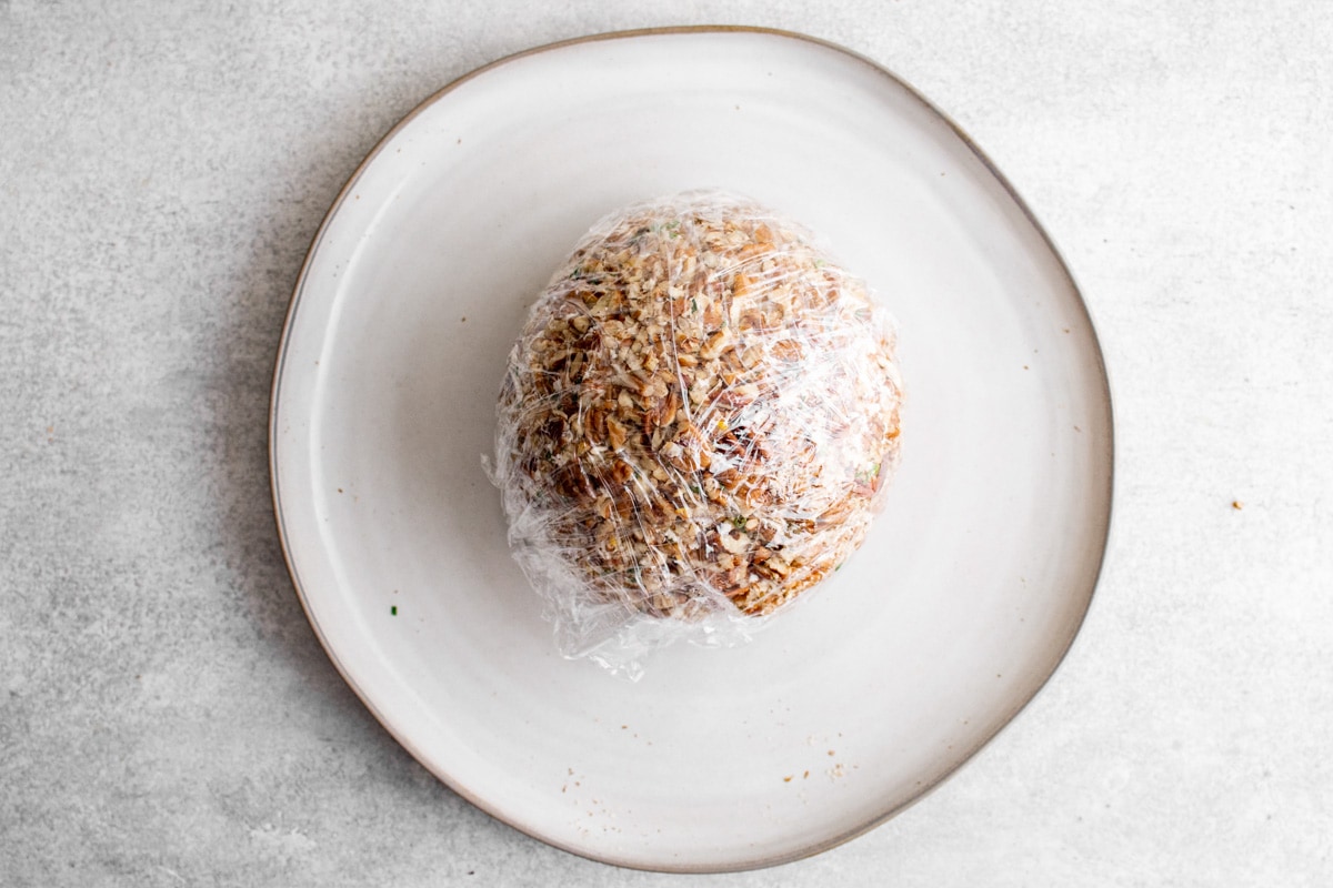 cheese ball coated in pecans and wrapped in plastic wrap