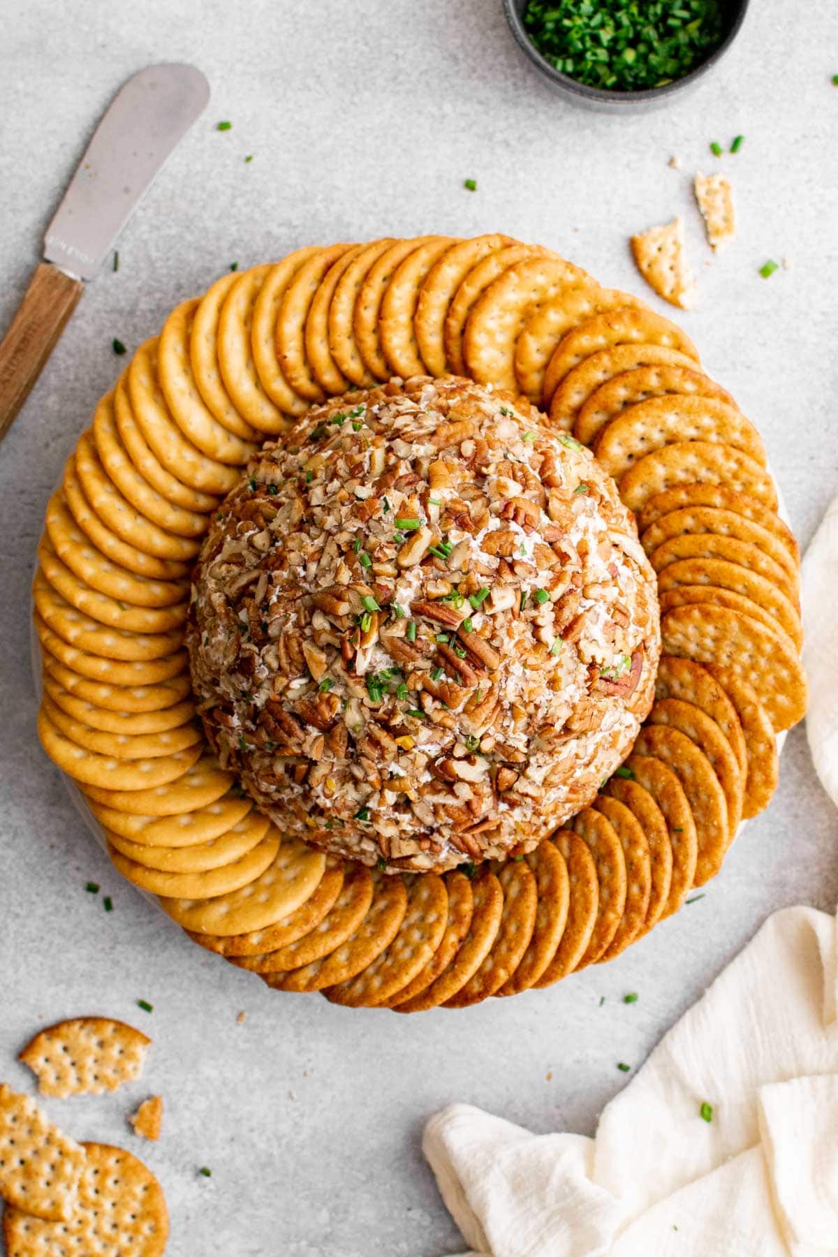 cheese ball coated in pecans and surrounded by crackers