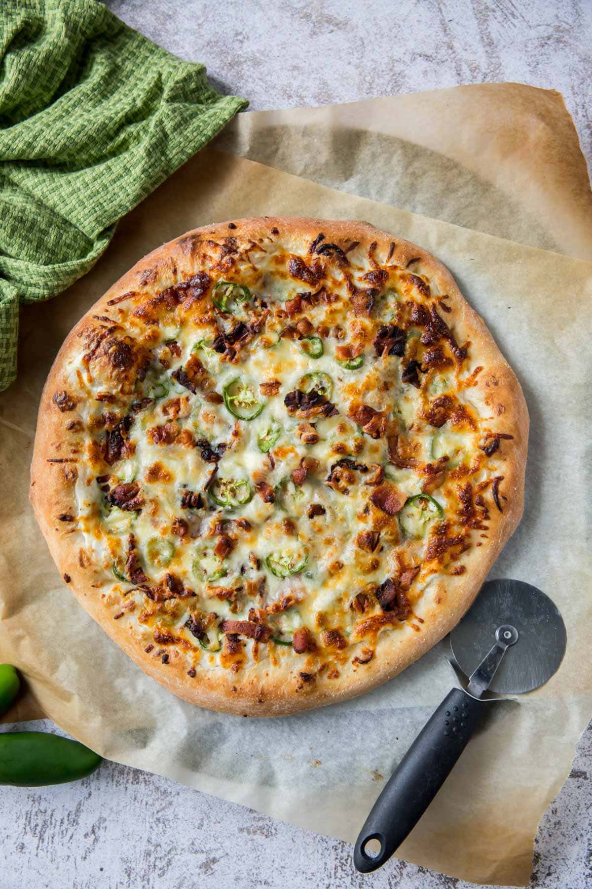 jalapeno pizza, green towel, pizza cutter