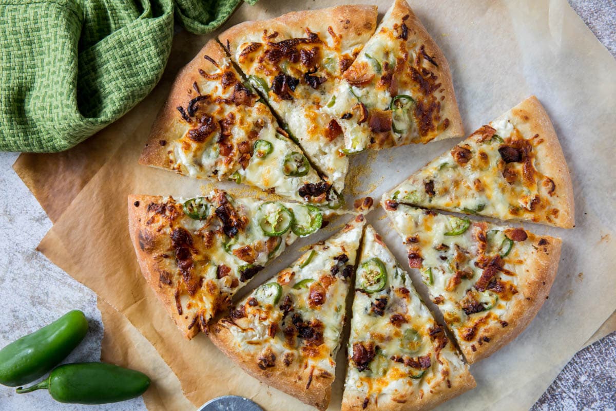 jalapeno pizza, sliced, with a bite out of one slice