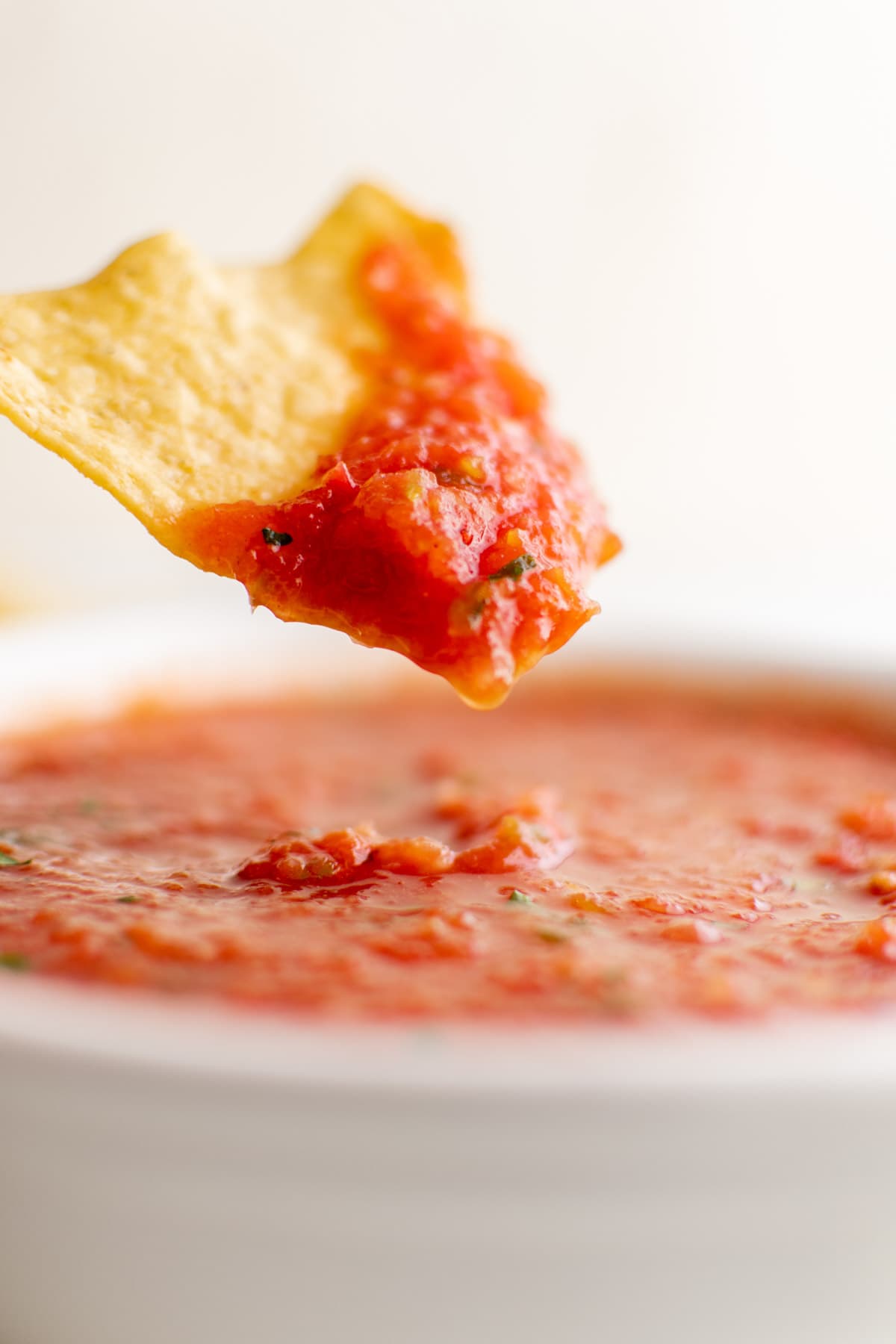 chip with salsa on it, bowl of restaurant style salsa
