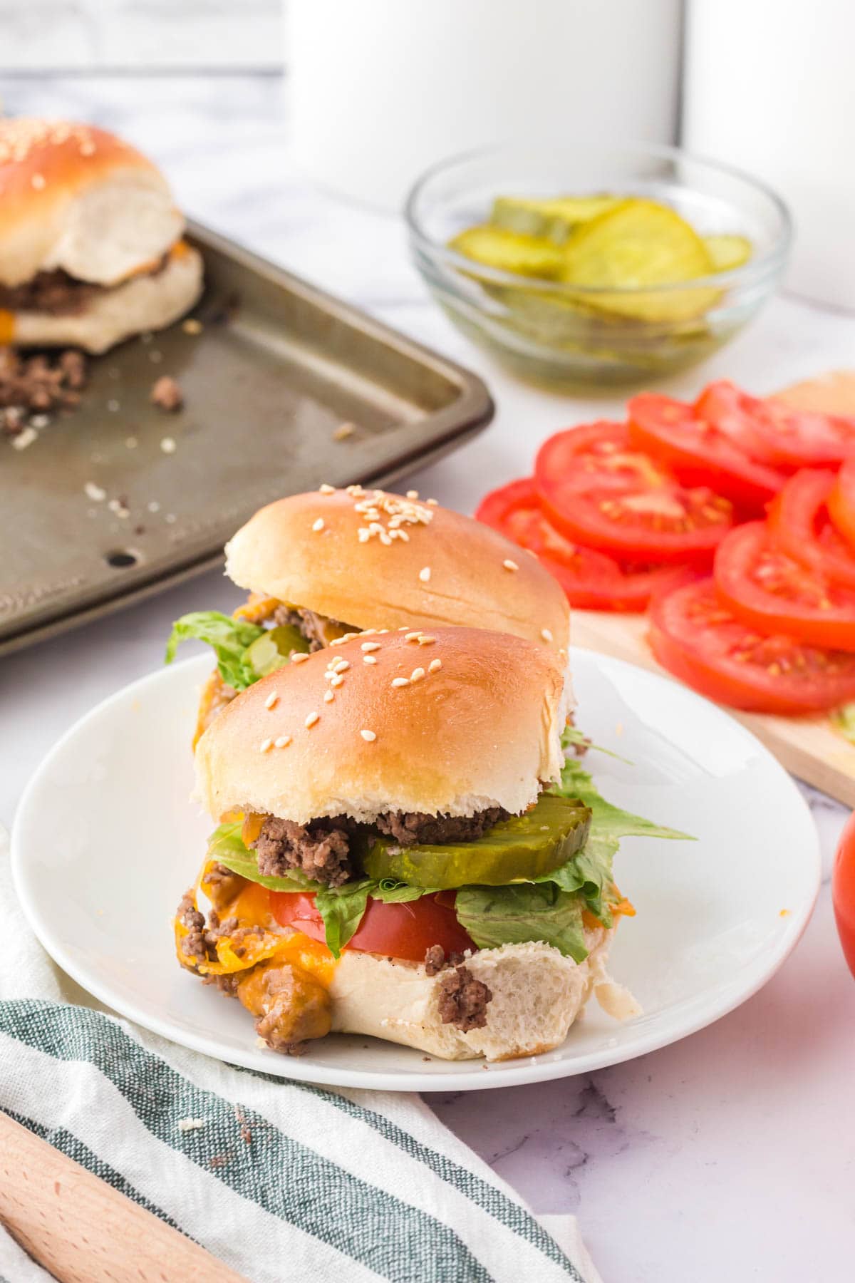 two cheeseburger sliders with toppings on a white plate