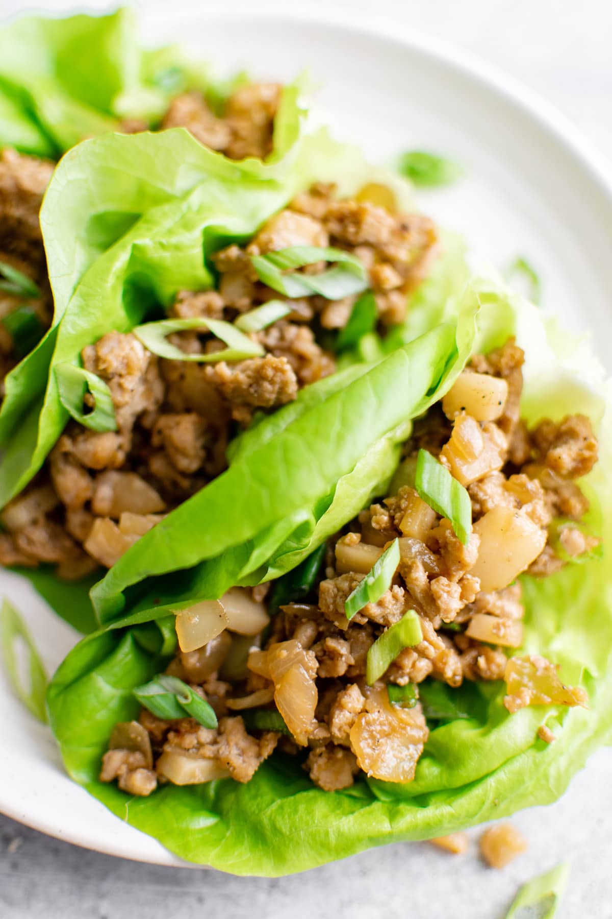stir fried ground chicken lettuce wraps on a white plate