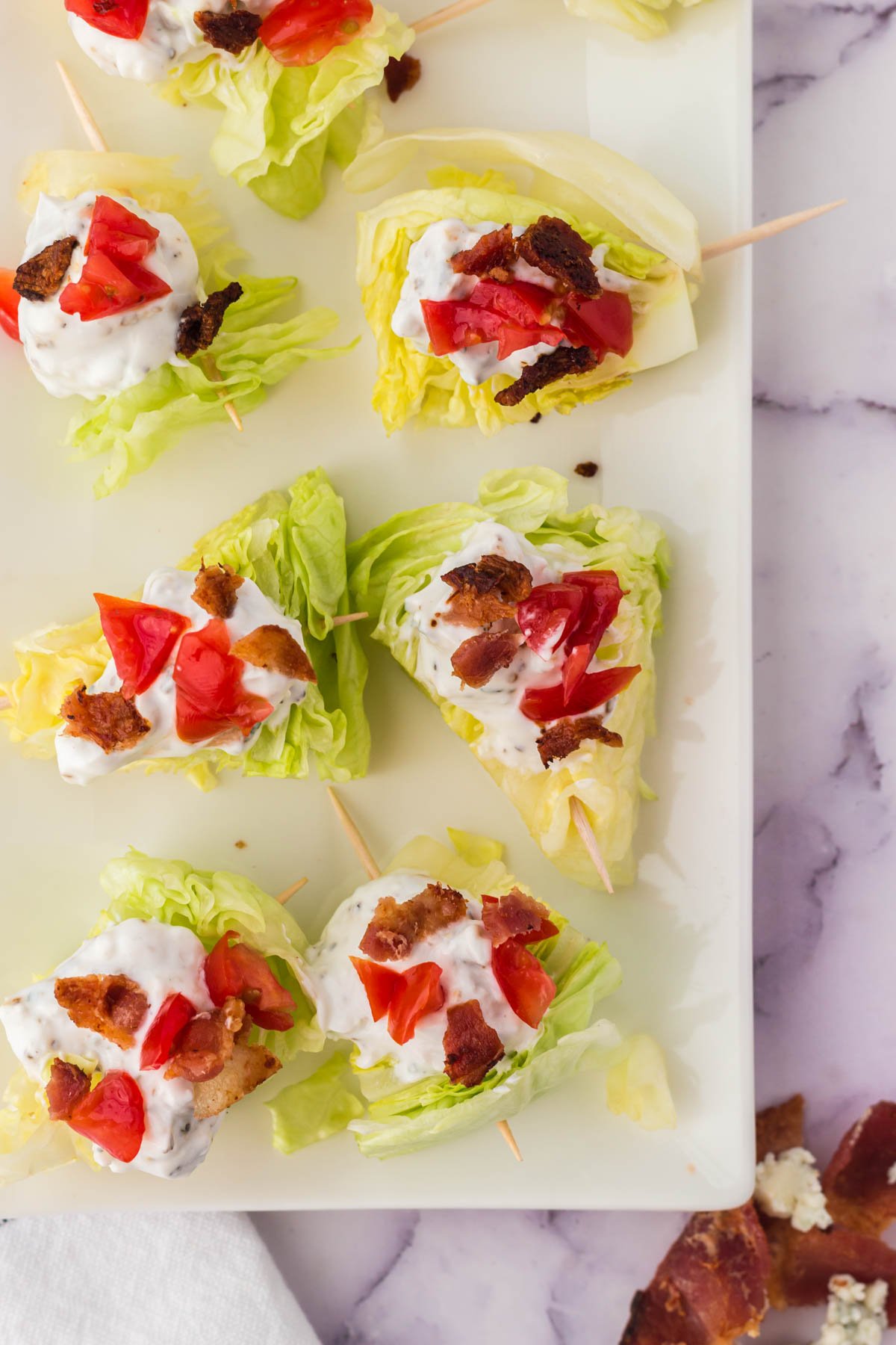 wedge salad bites on toothpicks with dressing, tomatoes and bacon