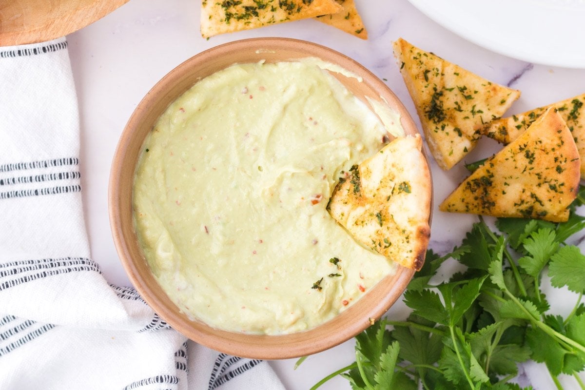 pita chip dipped in avocado dip