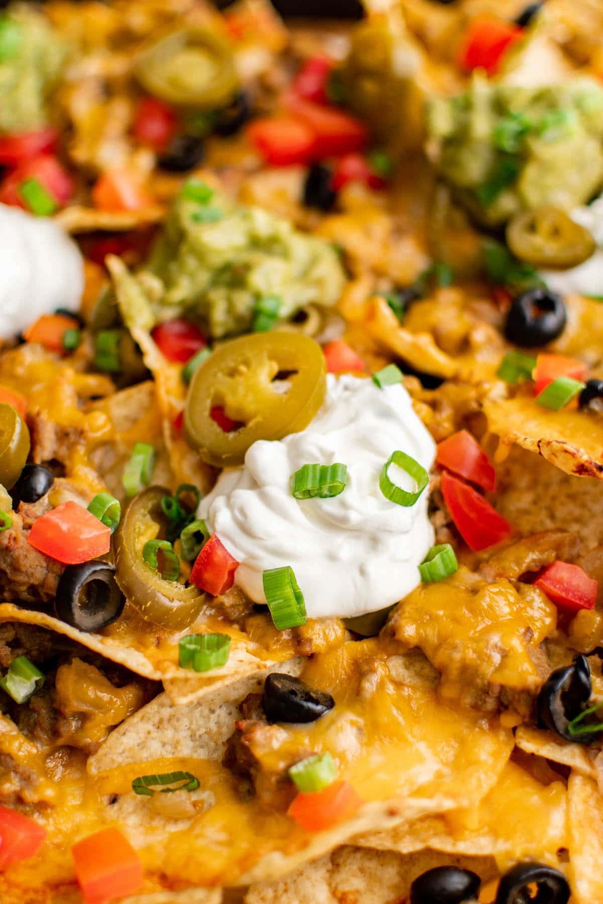 close up of nachos supreme with chips, sour cream cheese and other toppings