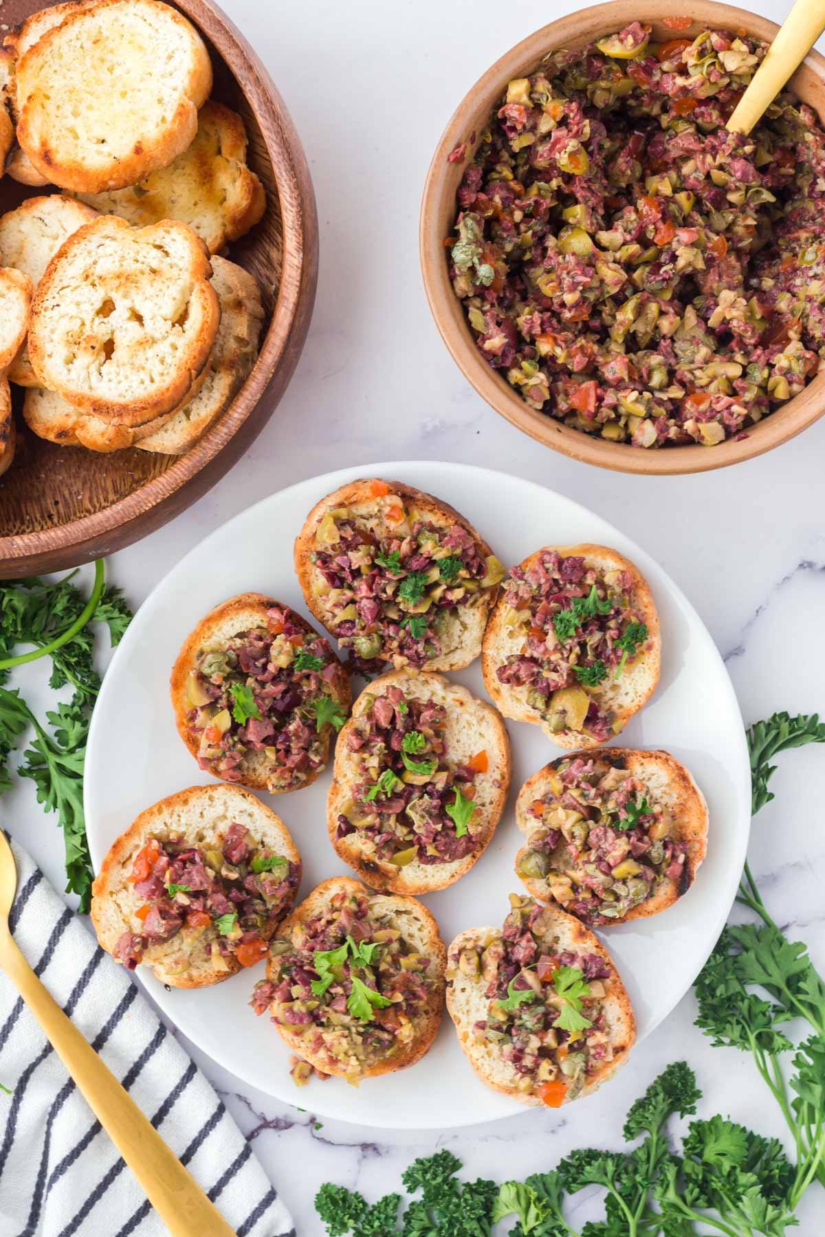 toasted bread topped with olive tapenade on a white plate