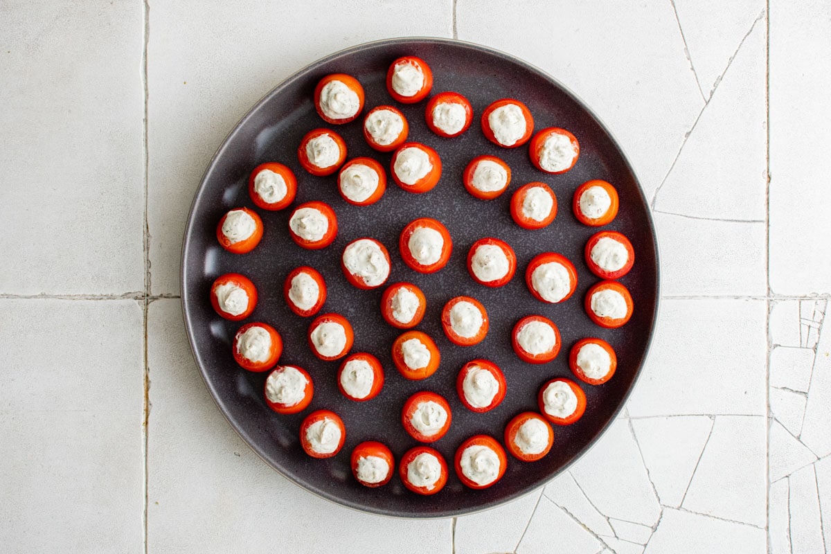 round black tray with cream cheese stuffed cherry tomatoes