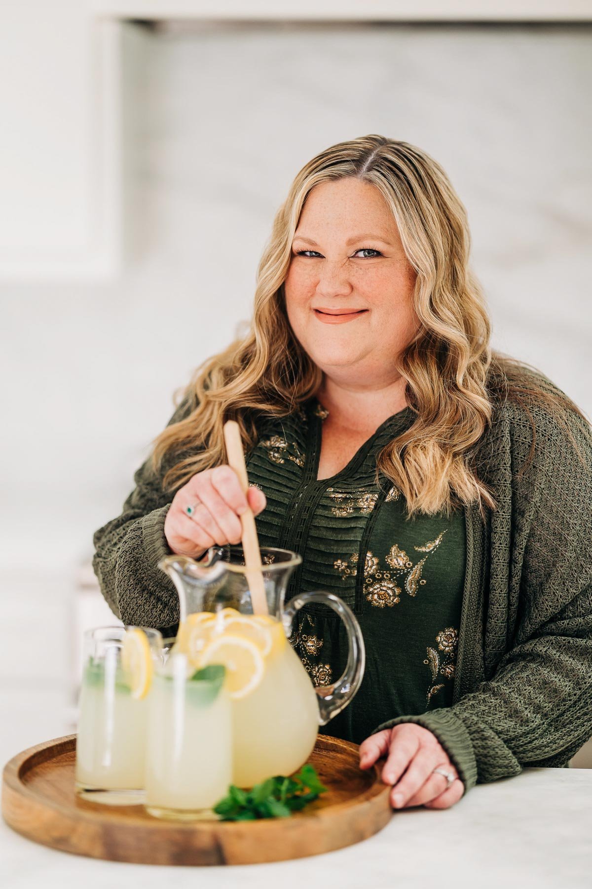 woman stirring a pitcher of lemonade