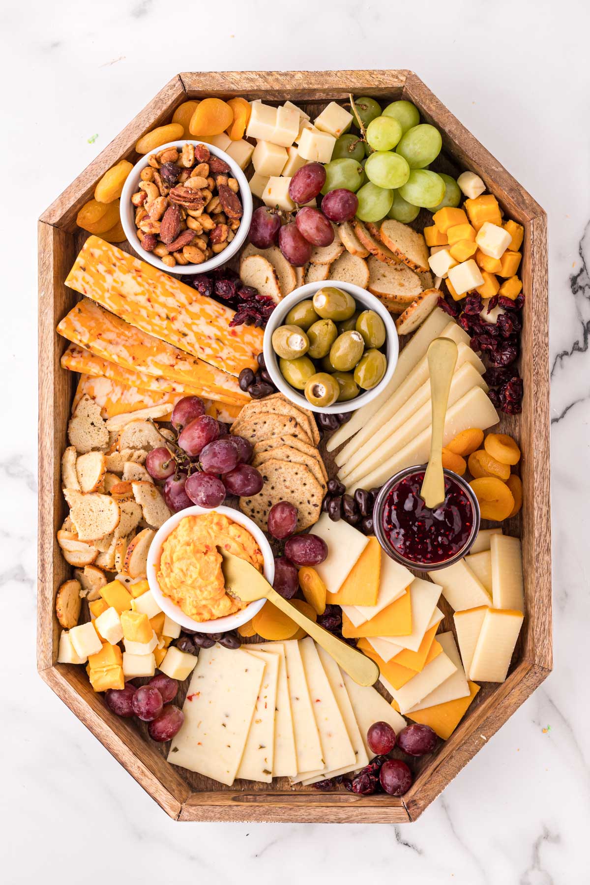 a cheese board with cheeses, fruits, nuts and spreads