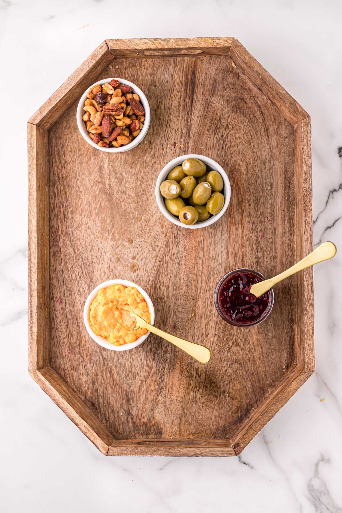 wood tray with little bowls of olives, nuts, spread cheese and jam