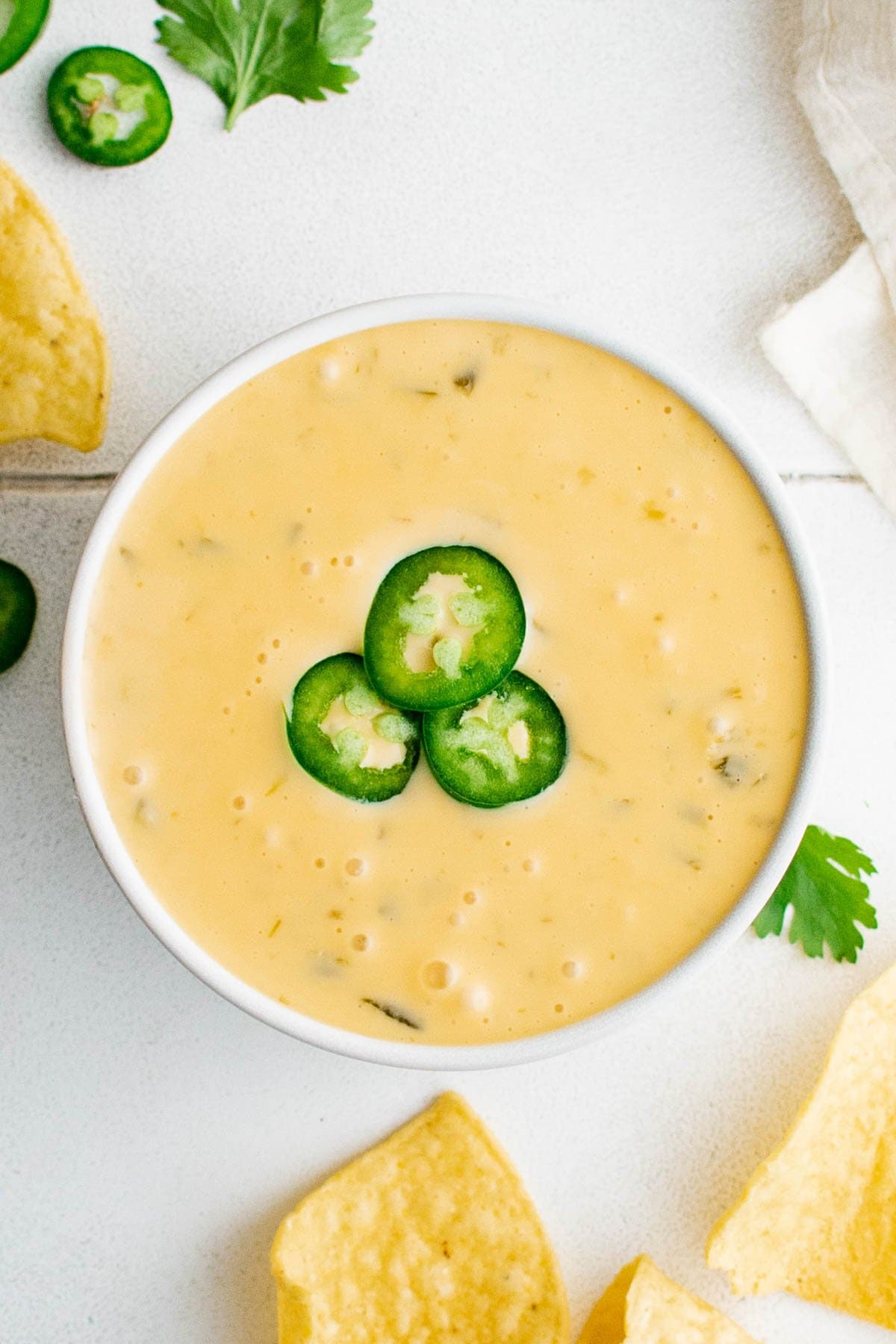 bowl of nacho cheese with sliced jalapenos