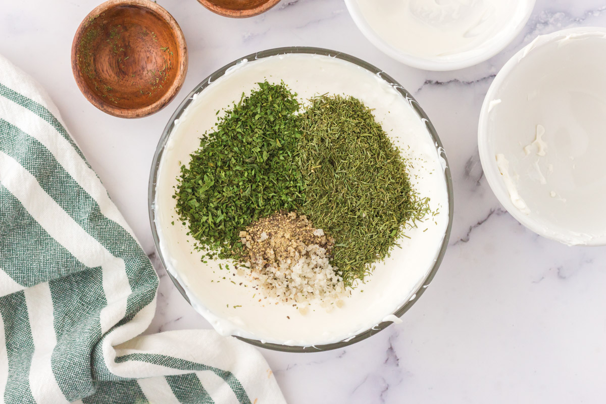 dried herbs added to sour cream in a bowl
