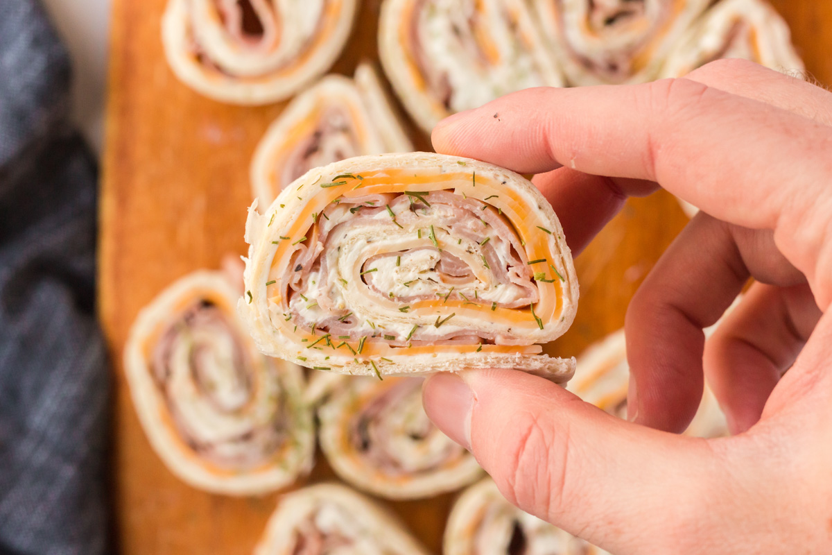 hand holding a puiece of a ham and cheese pinwheel