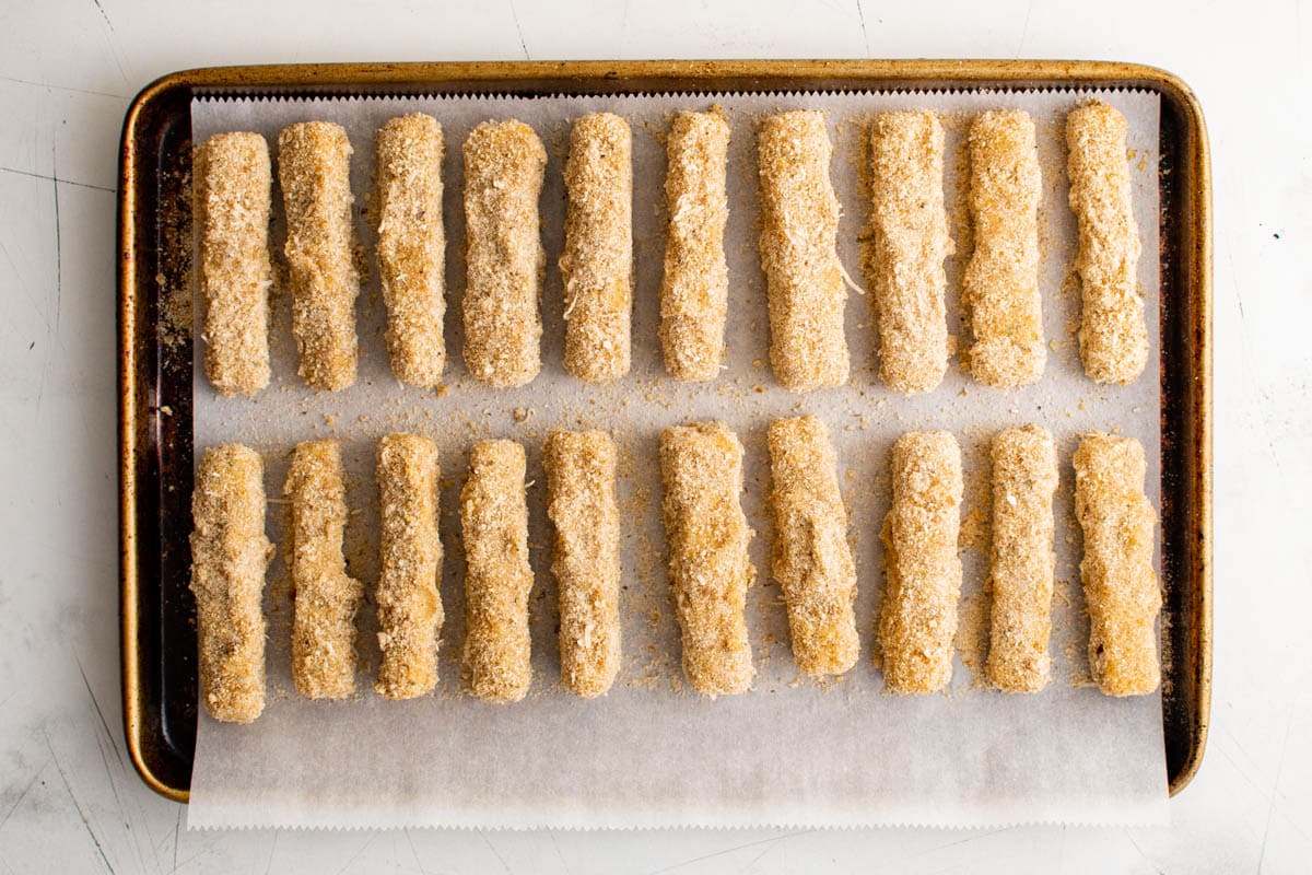 breaded mozzarella sticks on a sheet tray
