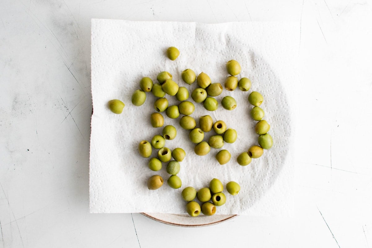 Green olives drying on paper towels.