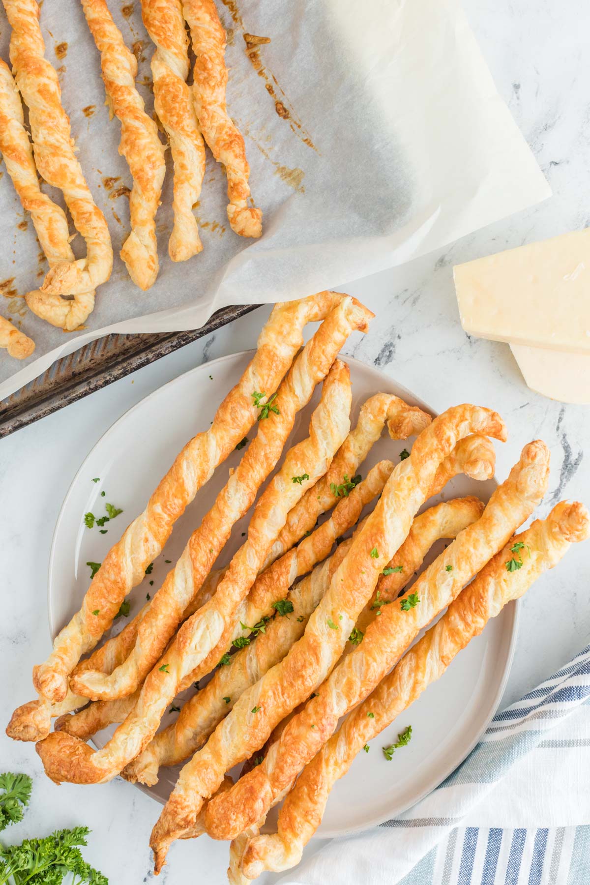 Cheese straws made from puff pastry on a white plate. 