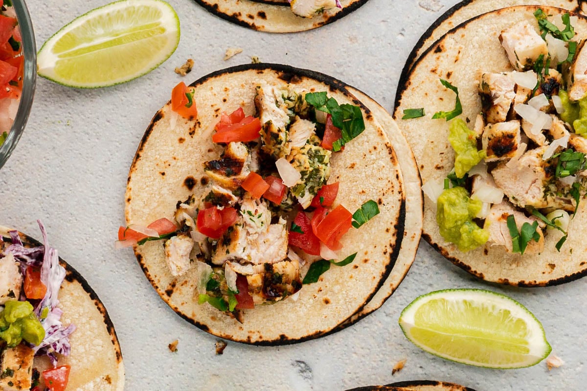 Close up of a flat corn tortilla with chicken and pico de gallo. 