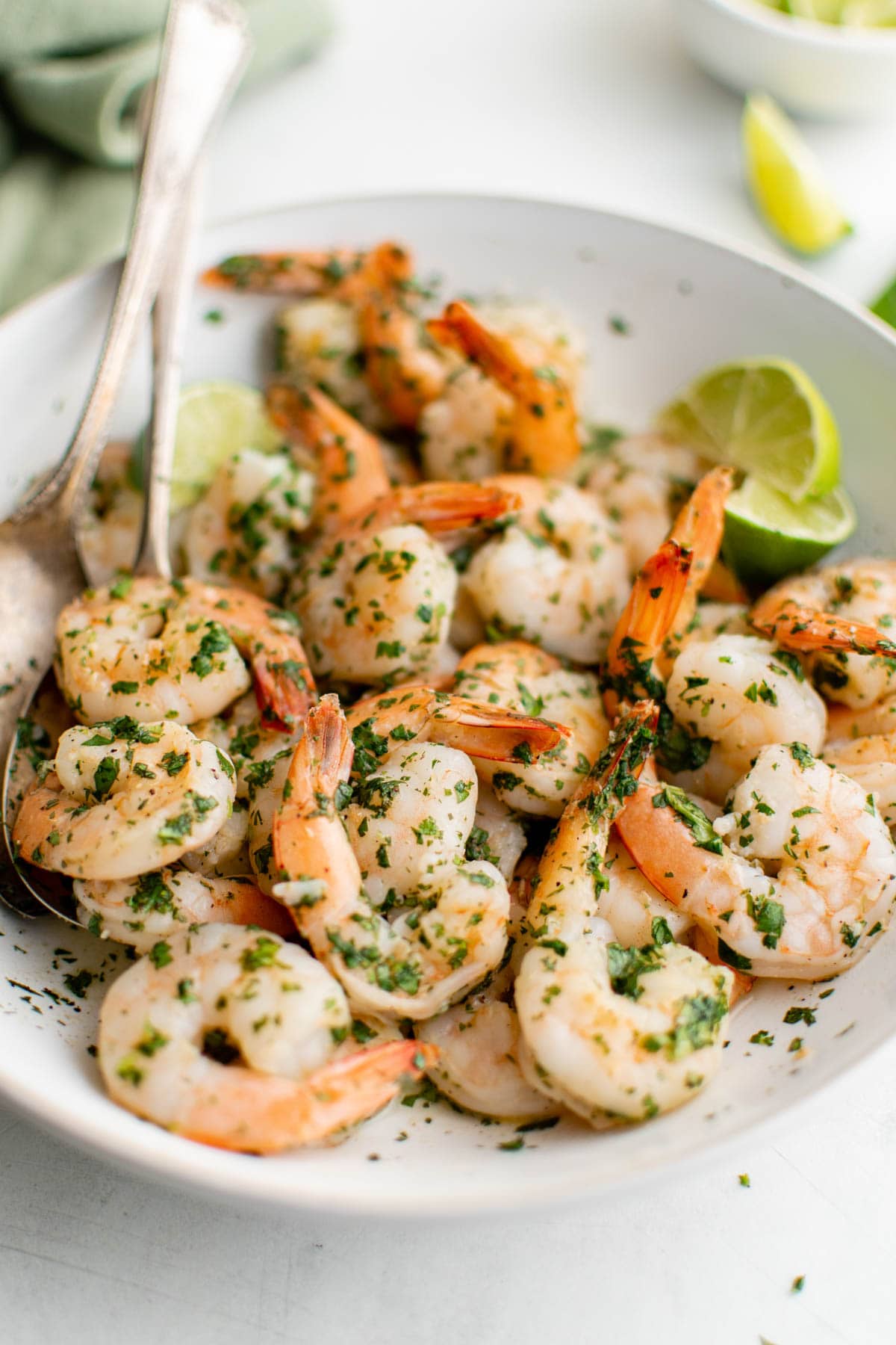 Close up of  cilantro lime shrimp in a large white bowl with a lime wedge. 