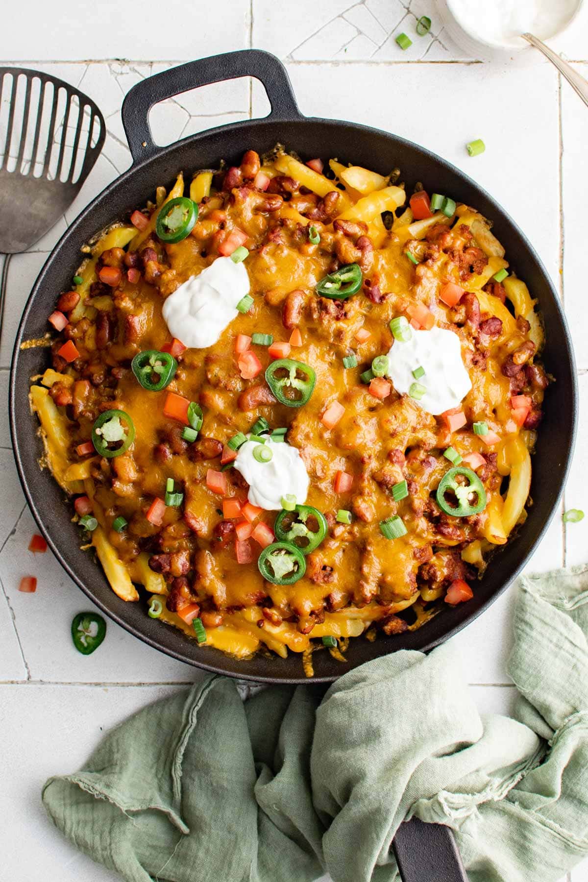 Cast iron skillet loaded with chili cheese french fries and toppings.