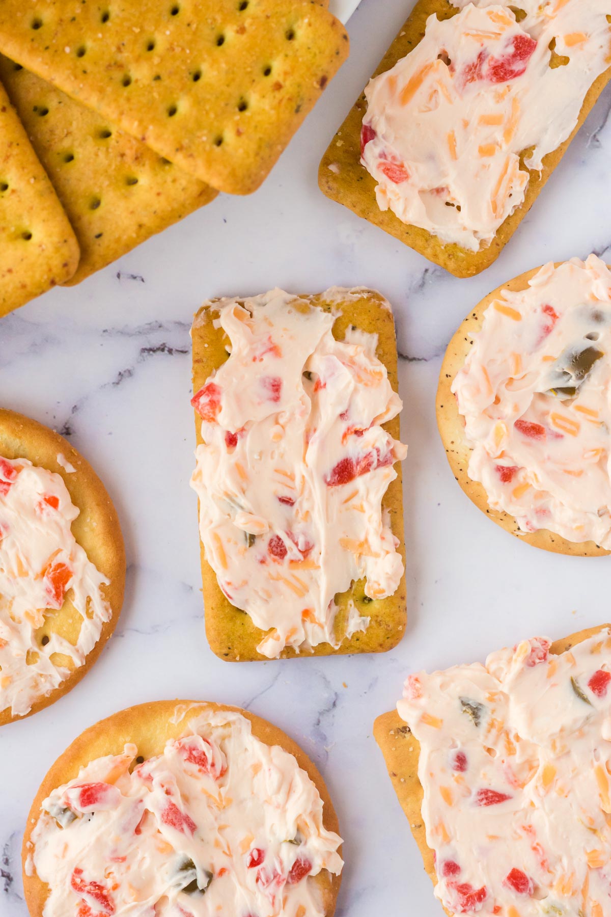Several Crackers spread out and spread with pimento cheese dip. 