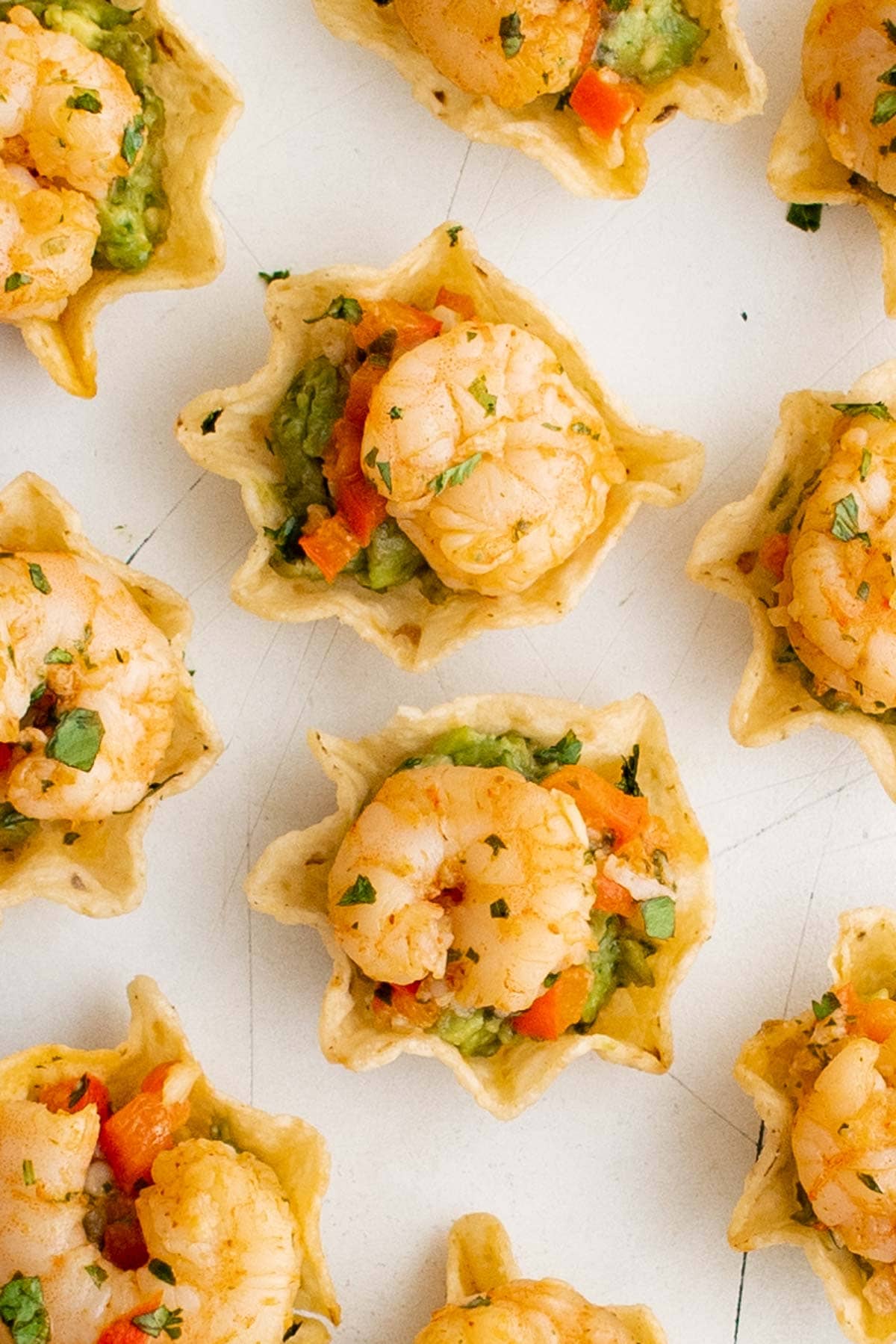 Shrimp in tostitos scoops tortilla chips with guacamole and bell pepper.