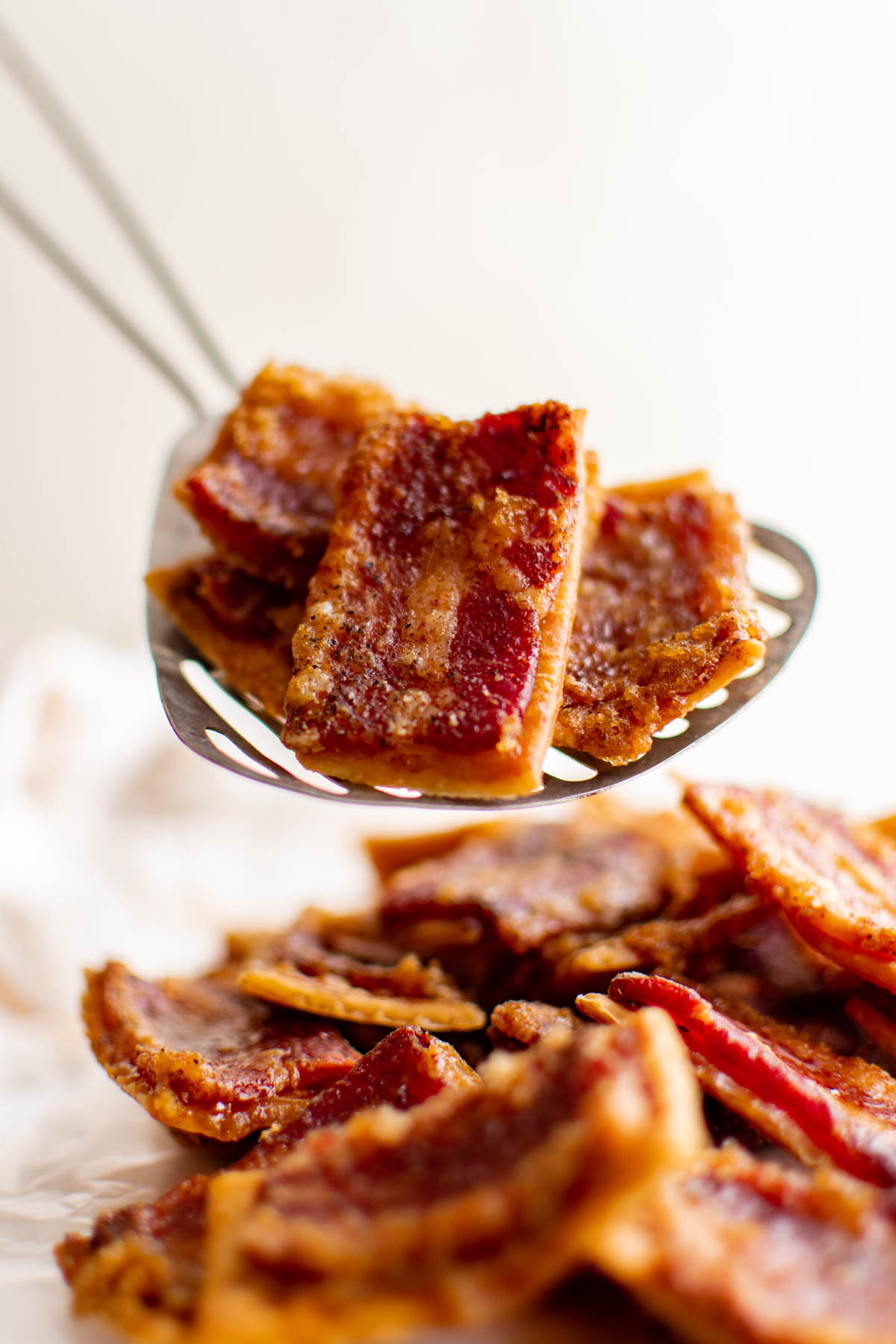 A large metal spoon with bacon crackers.