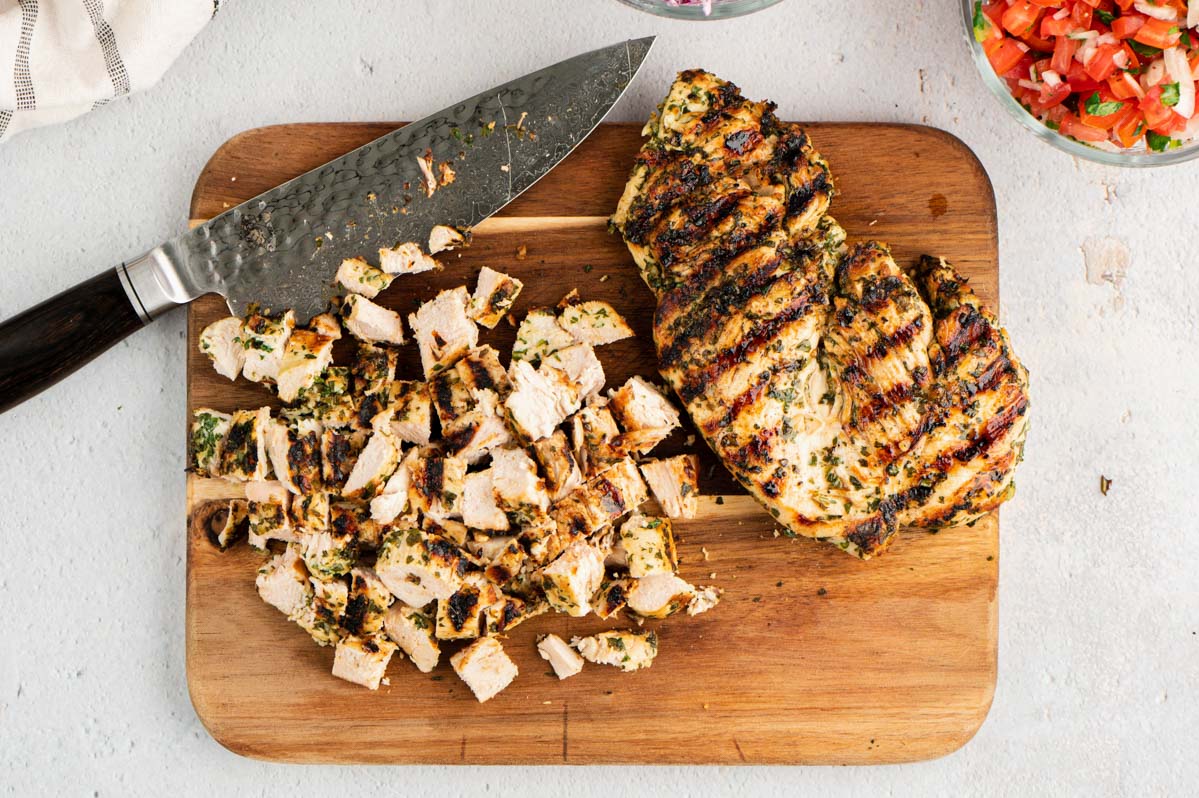 Grilled chicken chopped up on a cutting board.