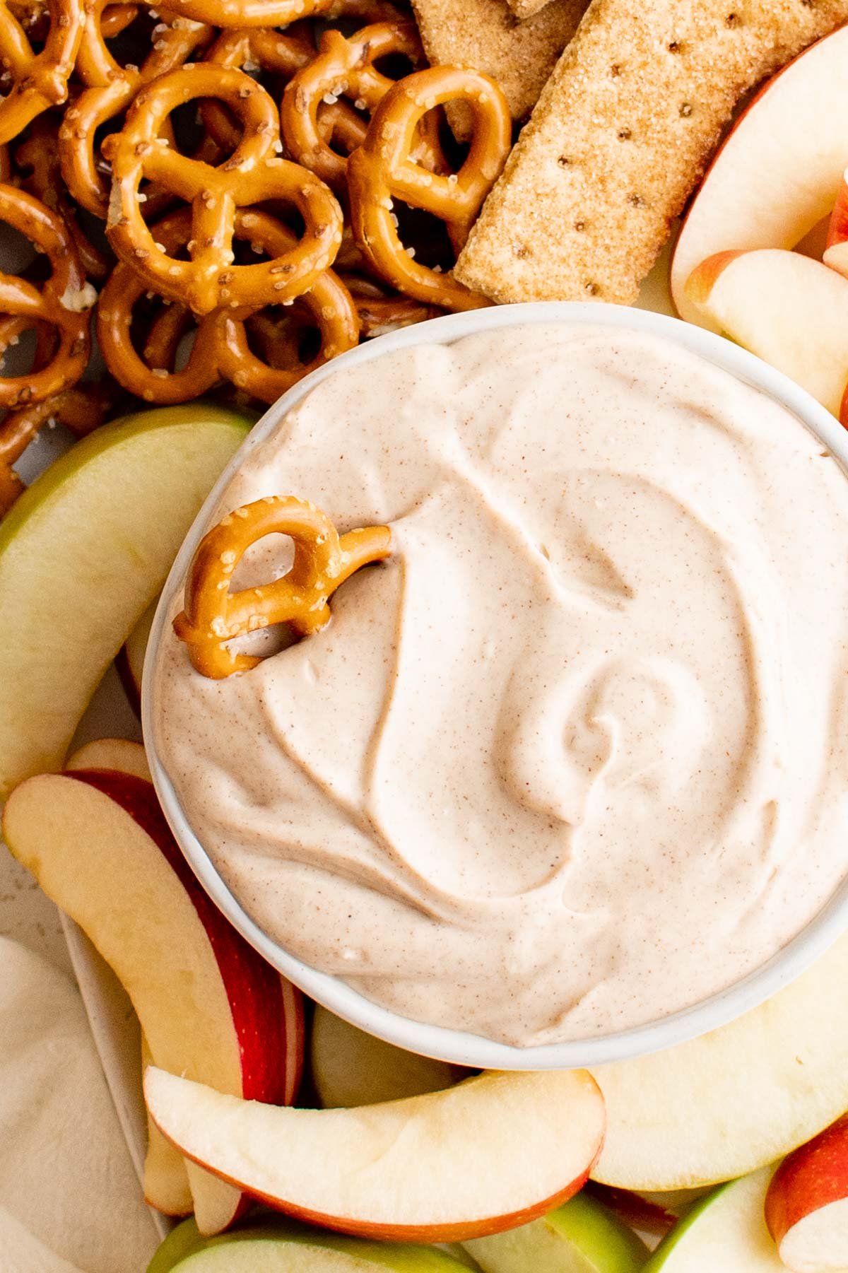 Bowl of cream cheese apple dip with a pretzel in it.
