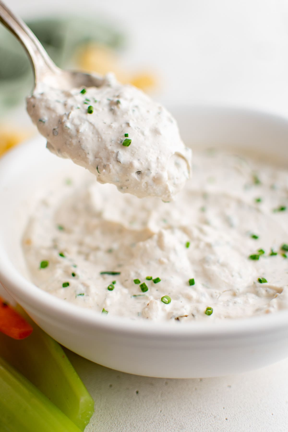 Sour cream chip dip in a white bowl with a spoon. 