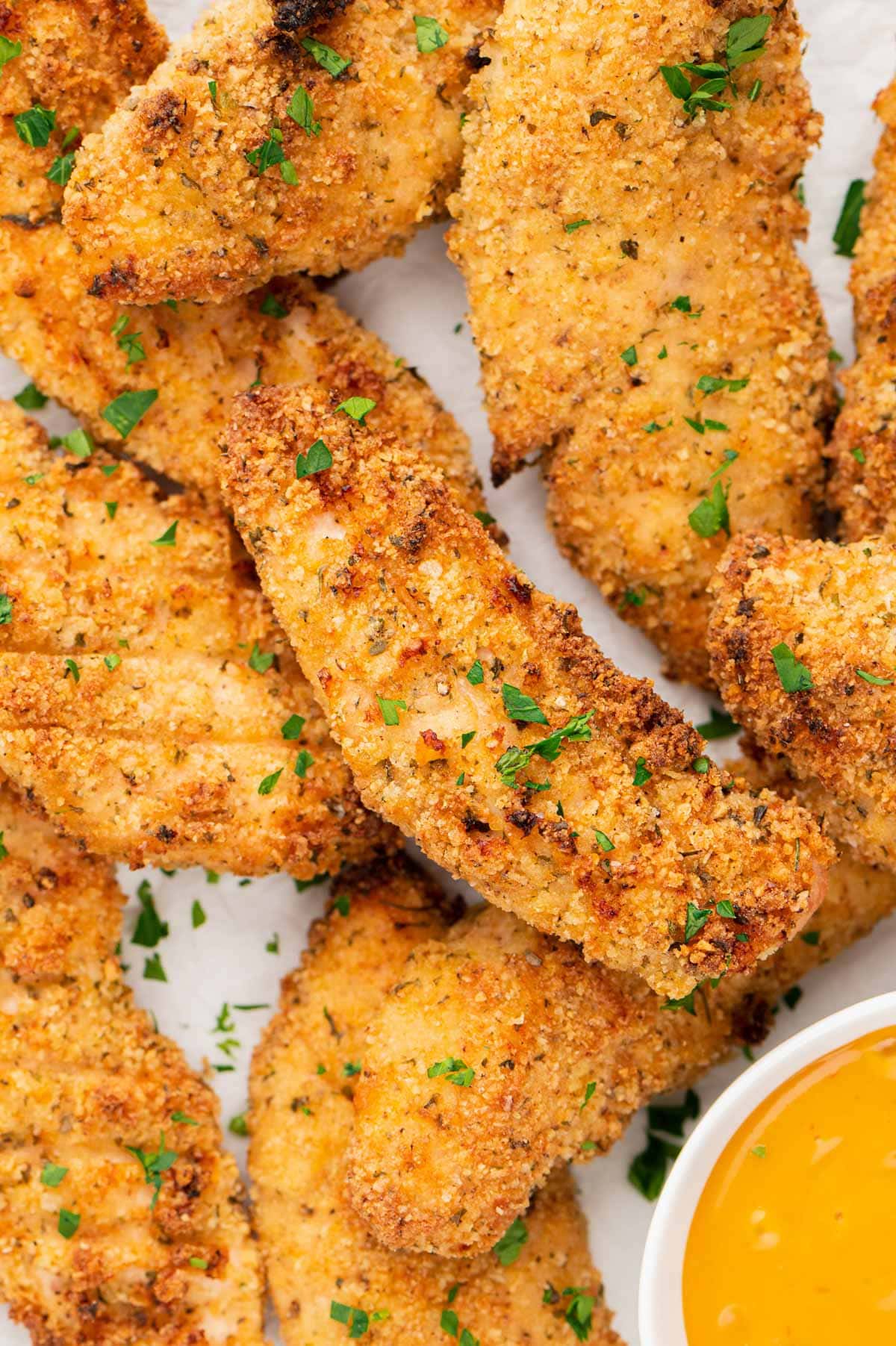Baked chicken tenders piled on a tray. 