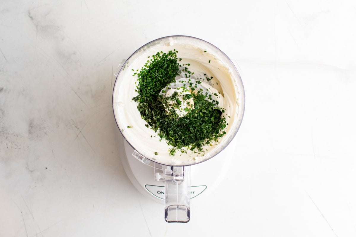 Food processor with cream cheese and herbs.