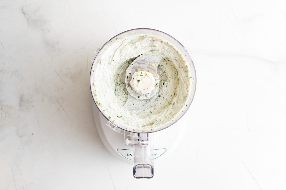 Cream cheese mixed with herbs in a food processor.
