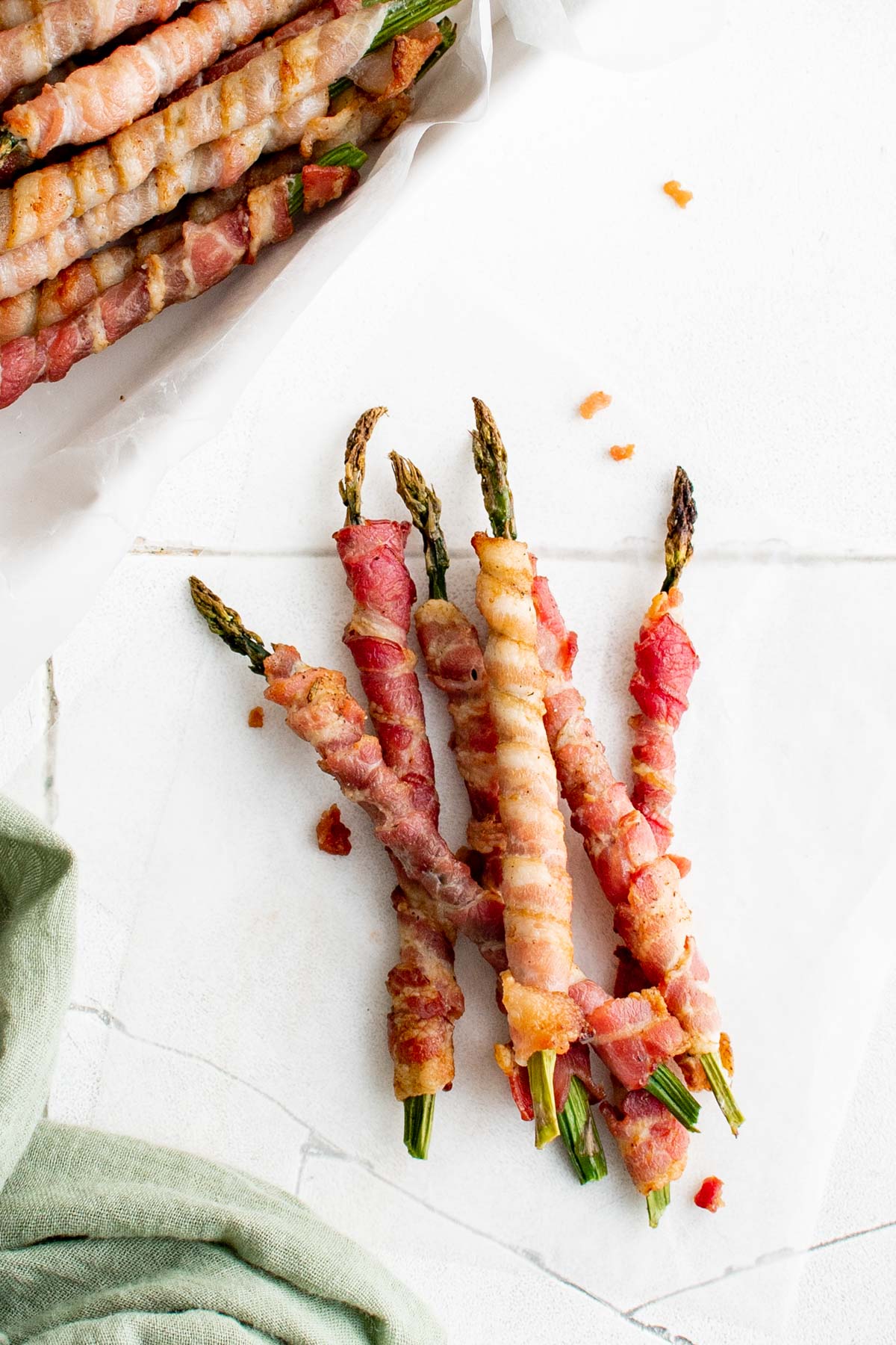 A few pieces of asparagus wrapped with bacon on a white background.