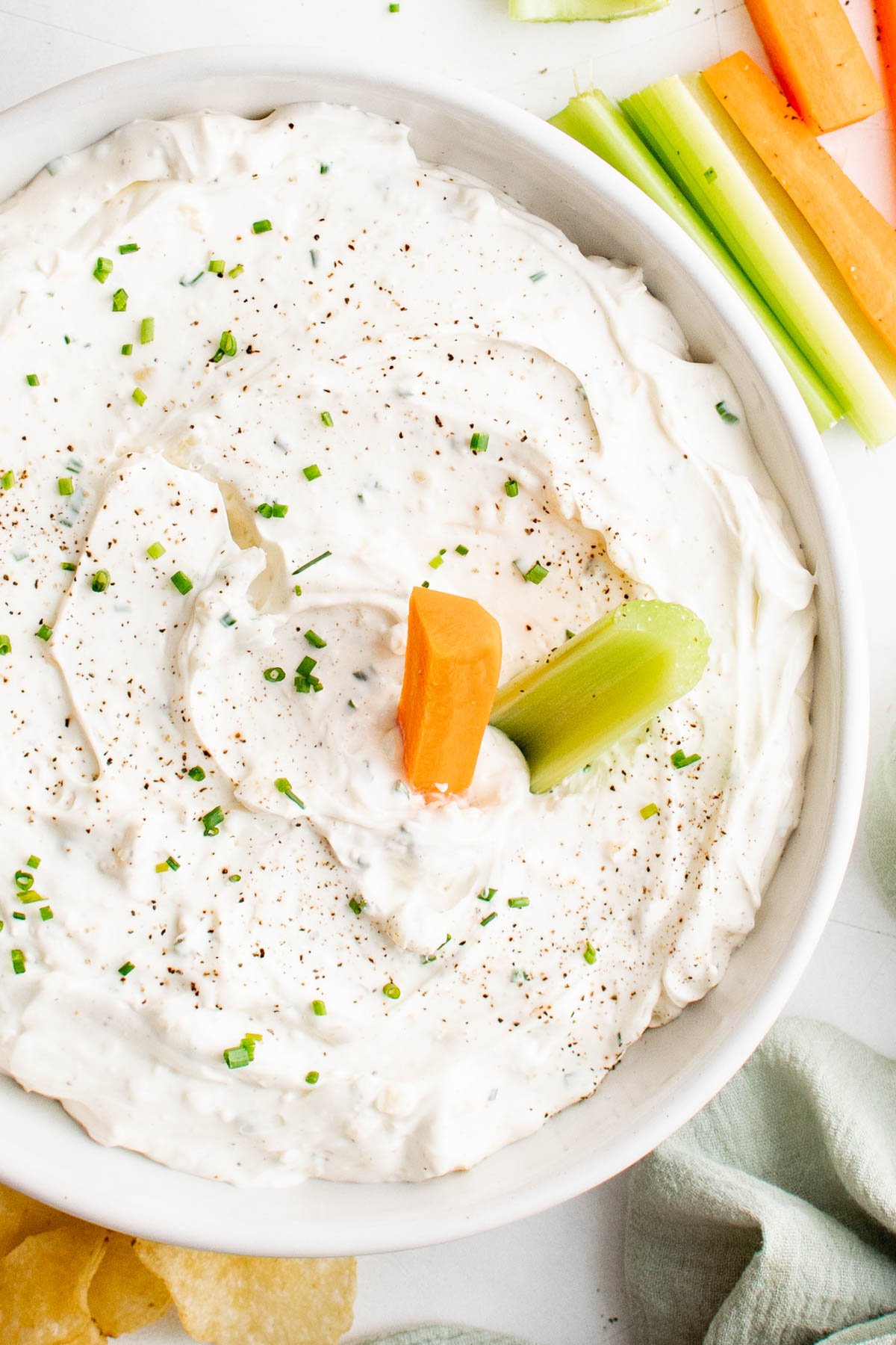 bowl of garlic dip with a carrot and celery stick.