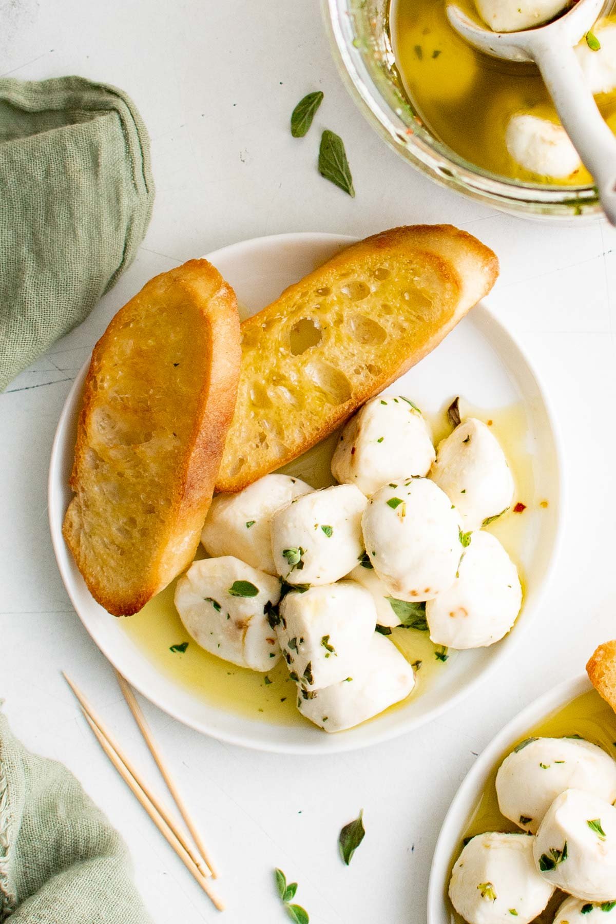 Mozzarella balls and toasted bread on a white plate.